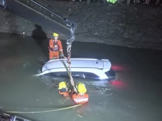 Petugas mengevakuasi Honda Mobilio yang nyemplung ke sungai menggunakan kendaraan penyelamatan.